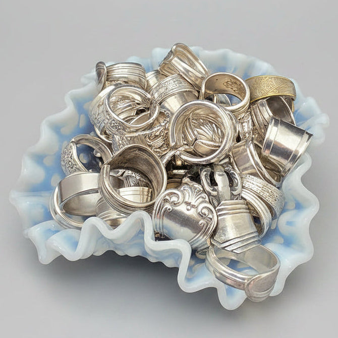 Collection of silver rings on a decorative blue and white ceramic dish against a gray background
